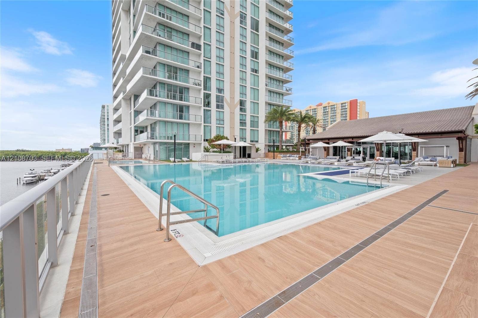 300 Sunny Isles Boulevard, #4-1501, Sunny Isles Beach, Sunny Isles Beach, FL 33160 Swimming pool with a tile surround, metal handrails, wood-finish decking, and high-rise exterior facade