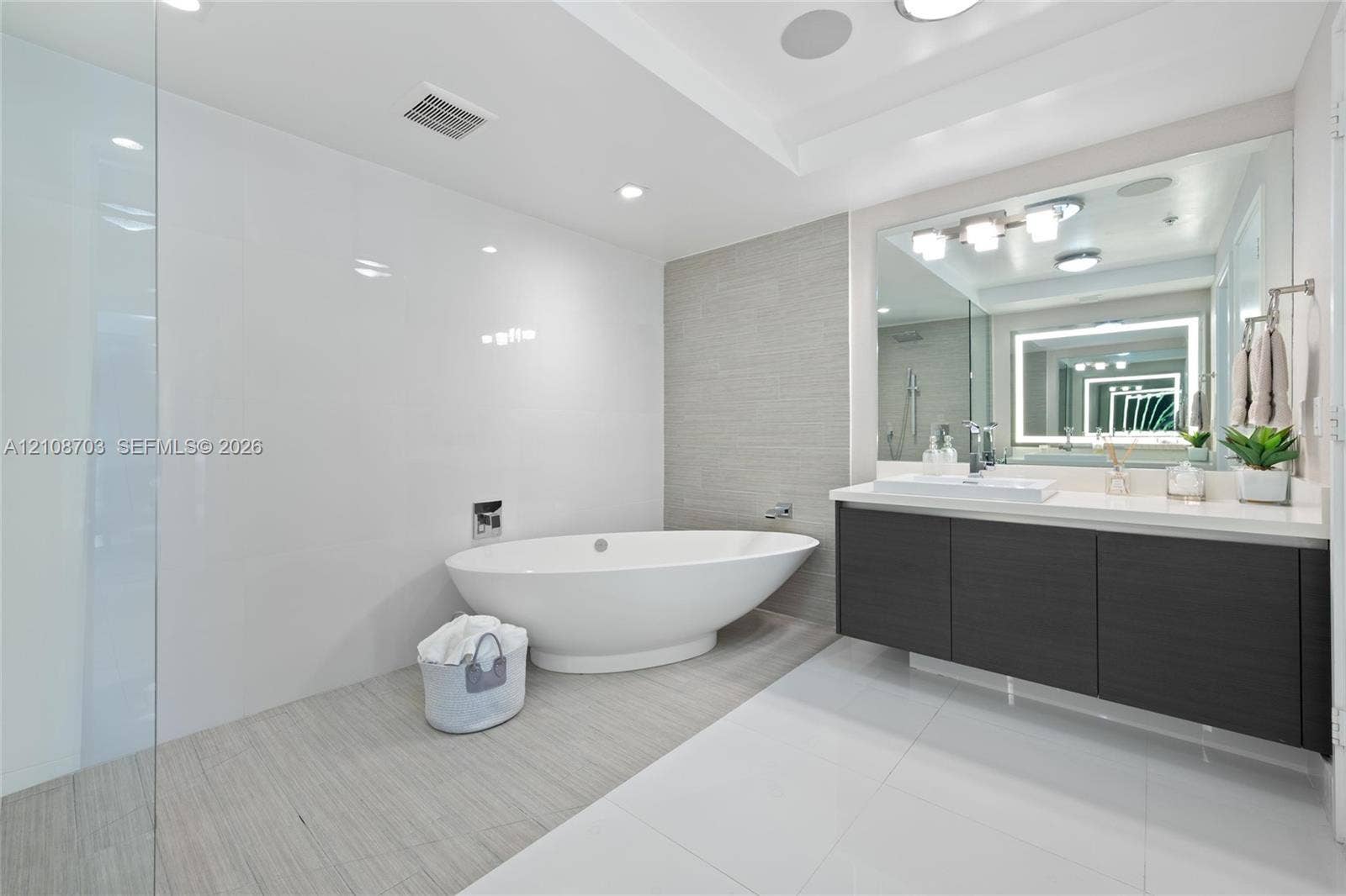 300 Sunny Isles Boulevard, #4-1501, Sunny Isles Beach, Sunny Isles Beach, FL 33160 Freestanding soaking tub, walk-in glass shower, wall-mounted vanity with integrated sink, large-format polished tile flooring, and textured tile accent wall