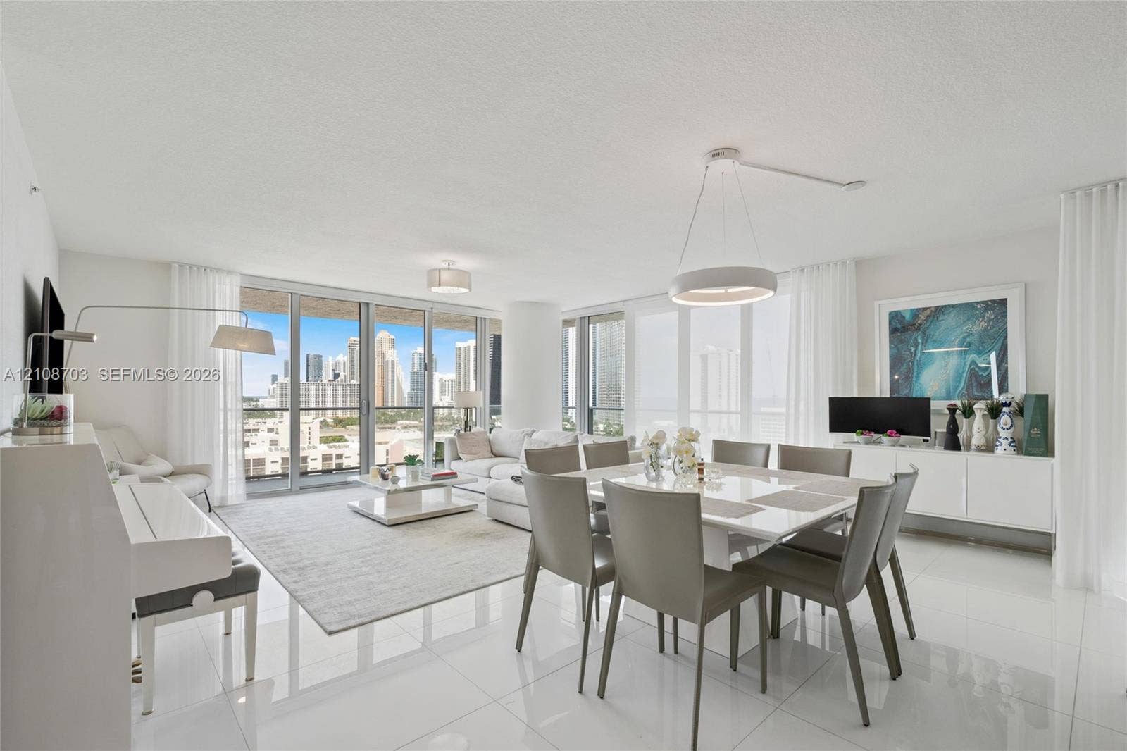 300 Sunny Isles Boulevard, #4-1501, Sunny Isles Beach, Sunny Isles Beach, FL 33160 Open-concept living area featuring polished tile flooring, floor-to-ceiling glass doors, and contemporary circular pendant lighting, accented by panoramic cityscape scenery