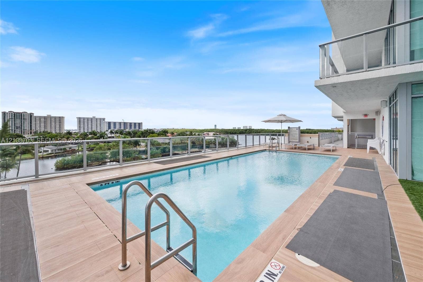 300 Sunny Isles Boulevard, #4-1501, Sunny Isles Beach, Sunny Isles Beach, FL 33160 Elevated swimming pool featuring wood-finish decking, metal railing, and stainless steel ladder