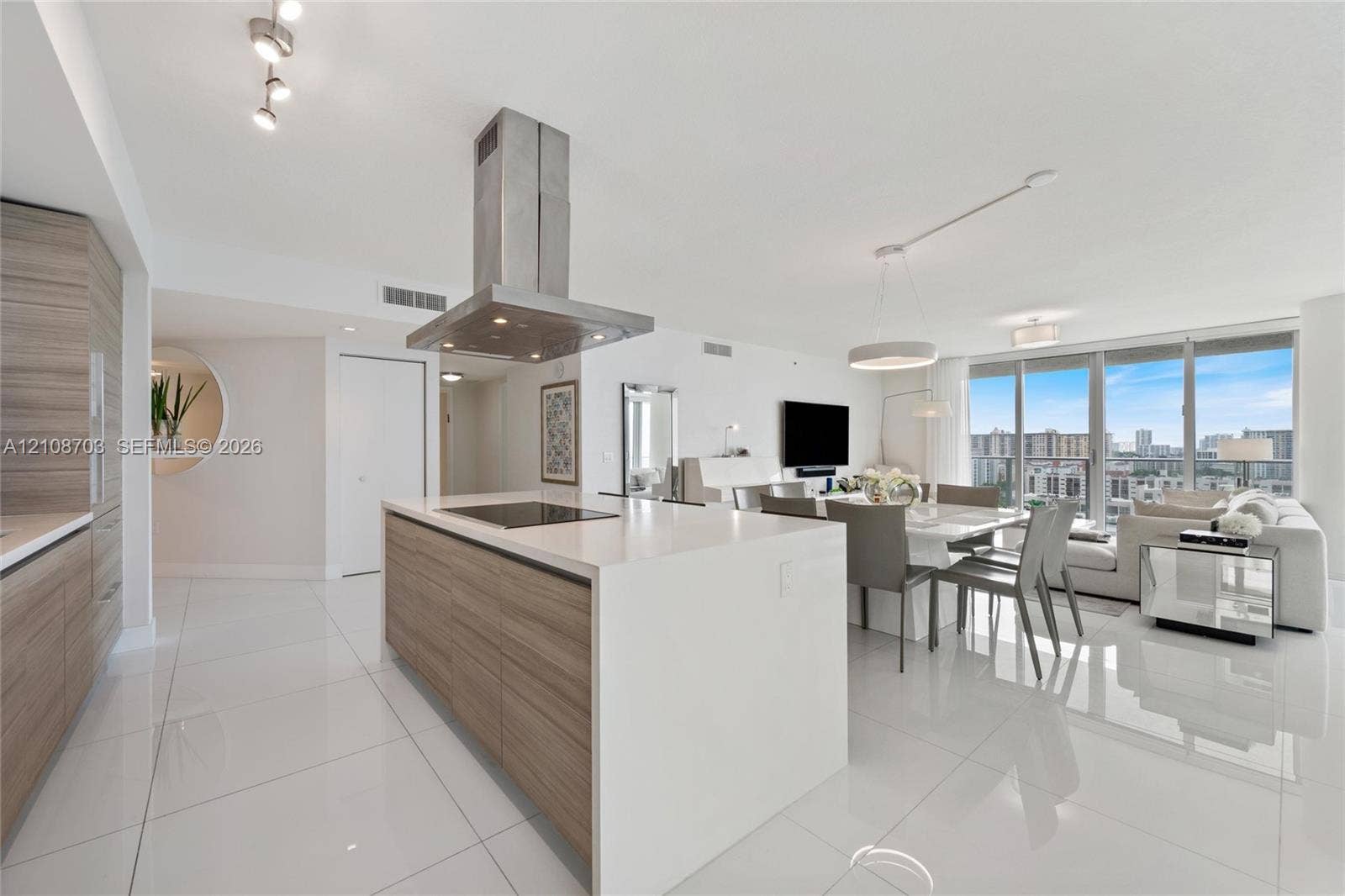 300 Sunny Isles Boulevard, #4-1501, Sunny Isles Beach, Sunny Isles Beach, FL 33160 Kitchen featuring a center island with a cooktop, stone-finish countertops, wood-finish cabinetry, a stainless steel chimney-style range hood, and large-format tile flooring