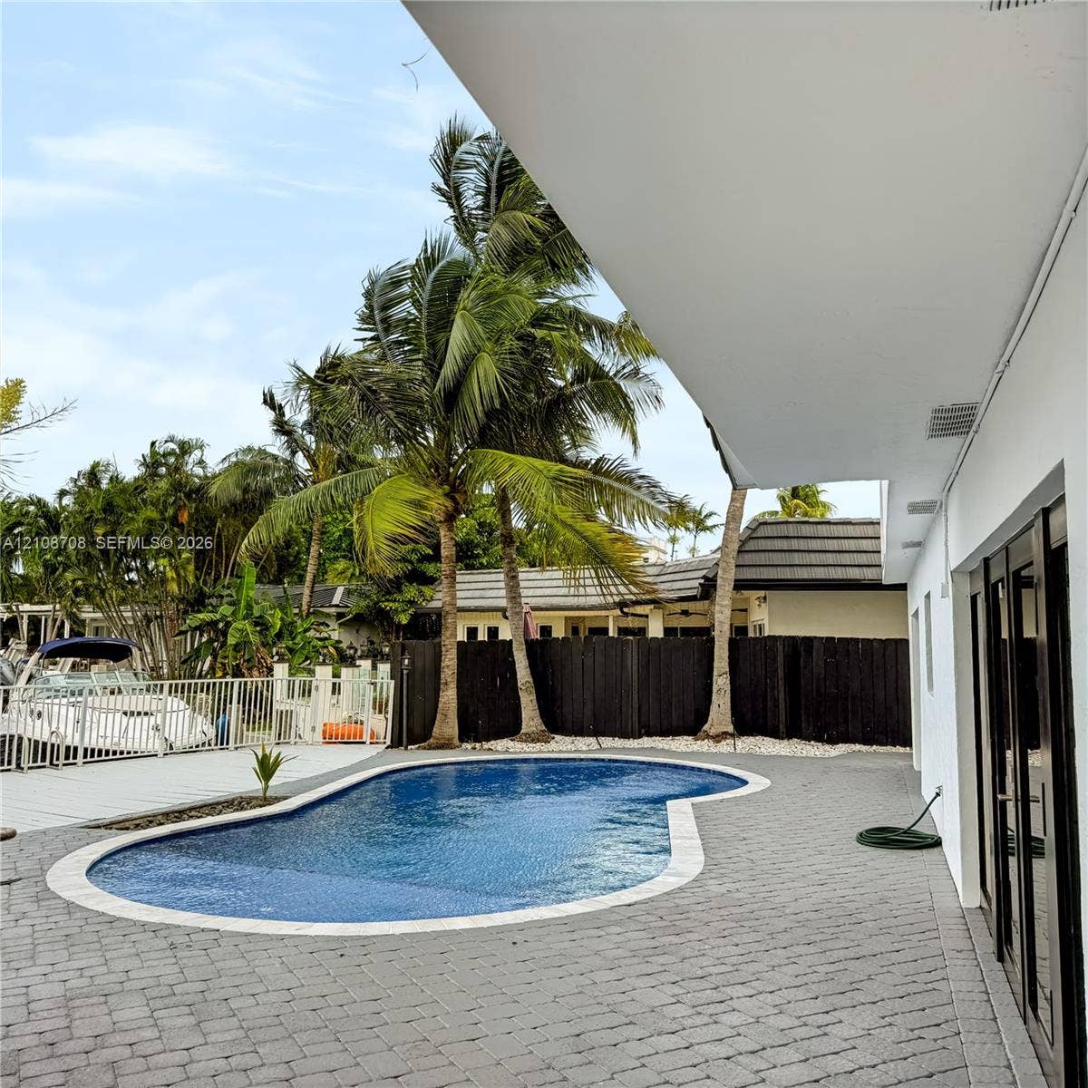 Pool and paver patio with boats along the canal behind