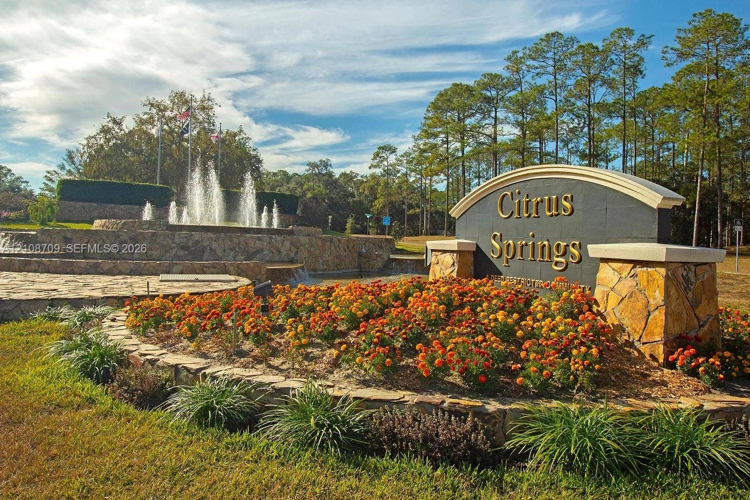 684 E Noah Lane, Citrus Springs, Citrus Springs, FL 34434 Community monument sign featuring decorative stonework, tiered water fountain, and manicured landscaping with floral beds