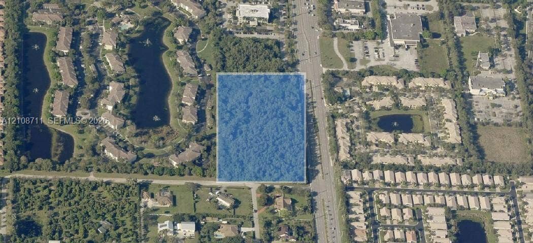 10195 S Jog Road, Boynton Beach, Boynton Beach, FL 33437 Rectangular parcel of undeveloped land featuring mature tree cover and direct frontage to a paved thoroughfare