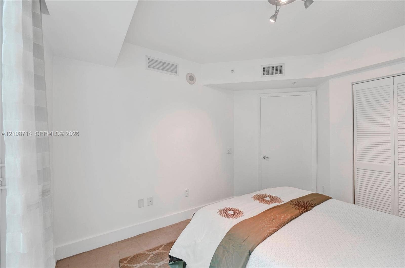 41 SE 5th Street, #317, Miami, Miami, FL 33131 Neutral interior room featuring white walls, white louvered closet doors, and a ceiling-mounted adjustable track light fixture