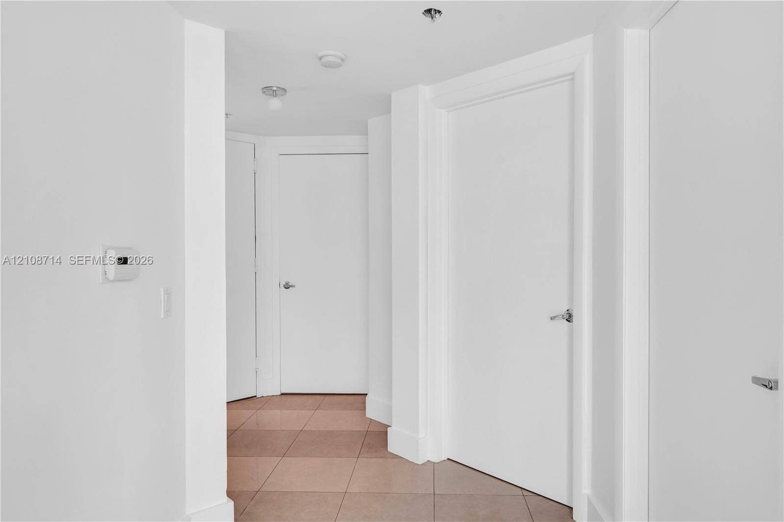 41 SE 5th Street, #317, Miami, Miami, FL 33131 Interior hallway featuring neutral-toned tile flooring, solid core doors with brushed metal hardware, and recessed lighting