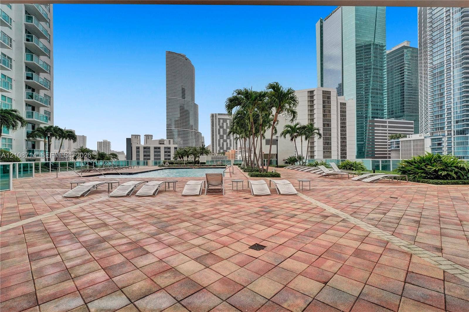 41 SE 5th Street, #317, Miami, Miami, FL 33131 Terrace area featuring paver flooring, an in-ground swimming pool, glass perimeter railing, and palm tree landscaping