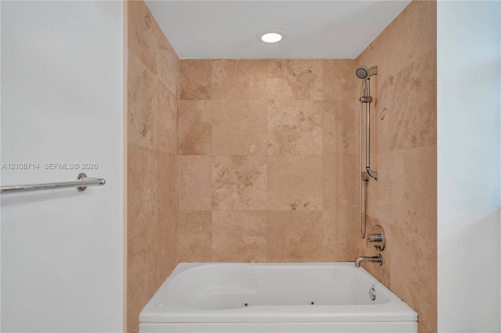 41 SE 5th Street, #317, Miami, Miami, FL 33131 Built-in jetted tub featuring stone-tile surround, adjustable handheld shower fixture, metal faucet, and recessed lighting