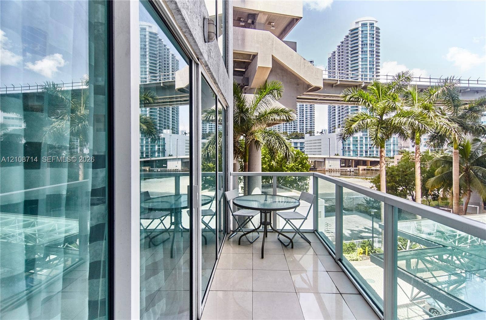 41 SE 5th Street, #317, Miami, Miami, FL 33131 Private balcony featuring large-format tile flooring, a glass-panel railing, and full-height floor-to-ceiling sliding glass doors