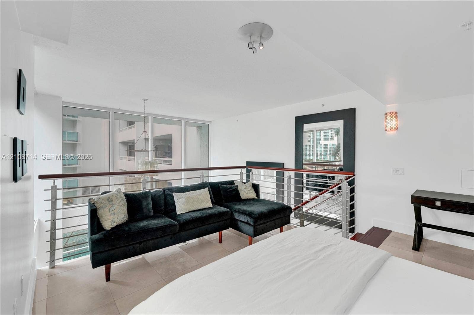 41 SE 5th Street, #317, Miami, Miami, FL 33131 Open-concept mezzanine featuring metal horizontal-rail balustrades with a dark wood handrail, large floor-to-ceiling windows, tile flooring, and integrated wall-mounted lighting