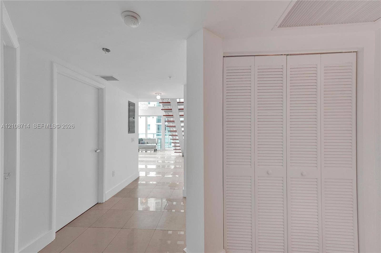 41 SE 5th Street, #317, Miami, Miami, FL 33131 Glossy tile flooring, louvered bi-fold closet doors, and a staircase with open risers