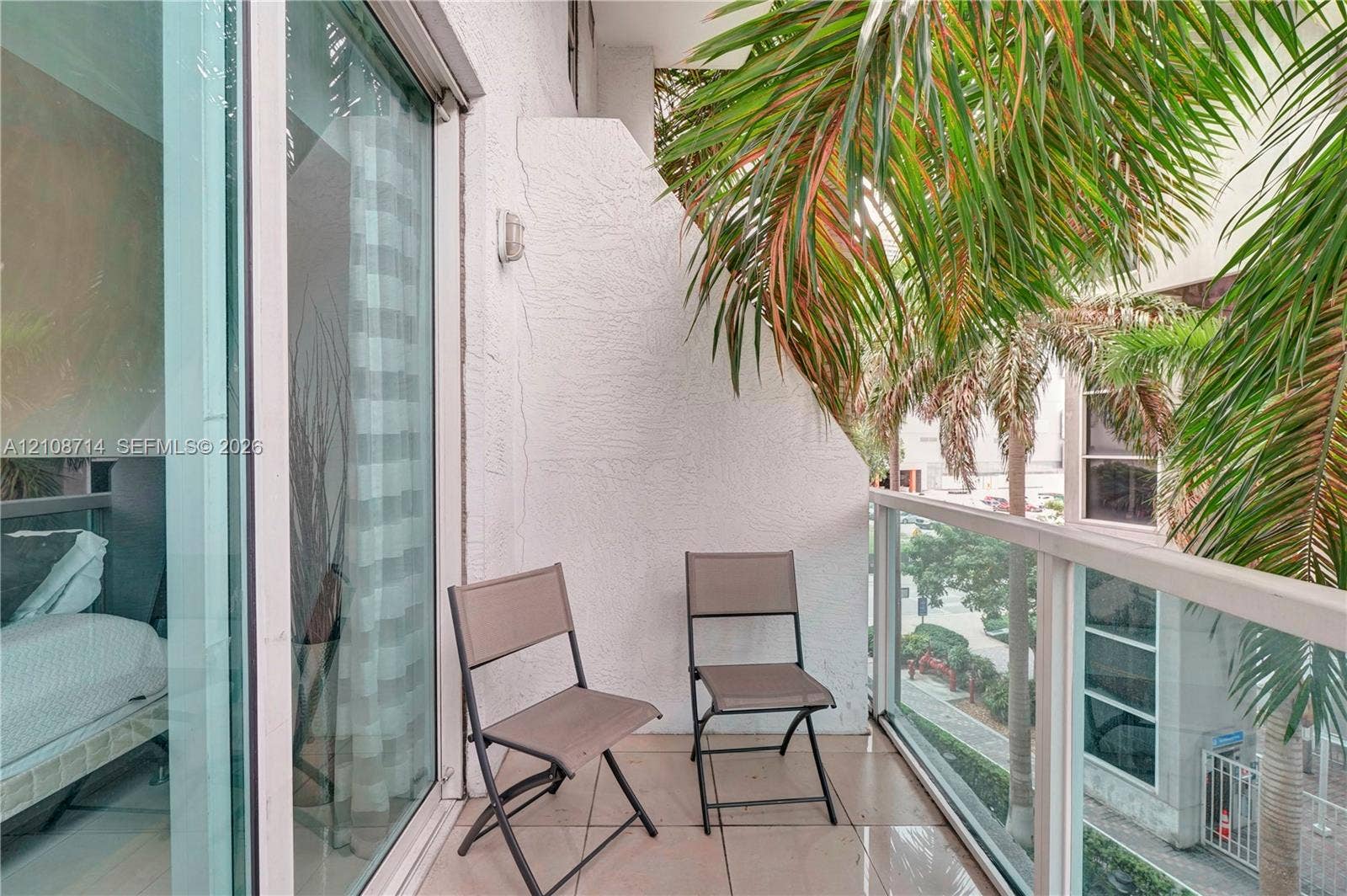 41 SE 5th Street, #317, Miami, Miami, FL 33131 Covered balcony featuring tile flooring, white stucco walls, and a glass-paneled railing with metal framing