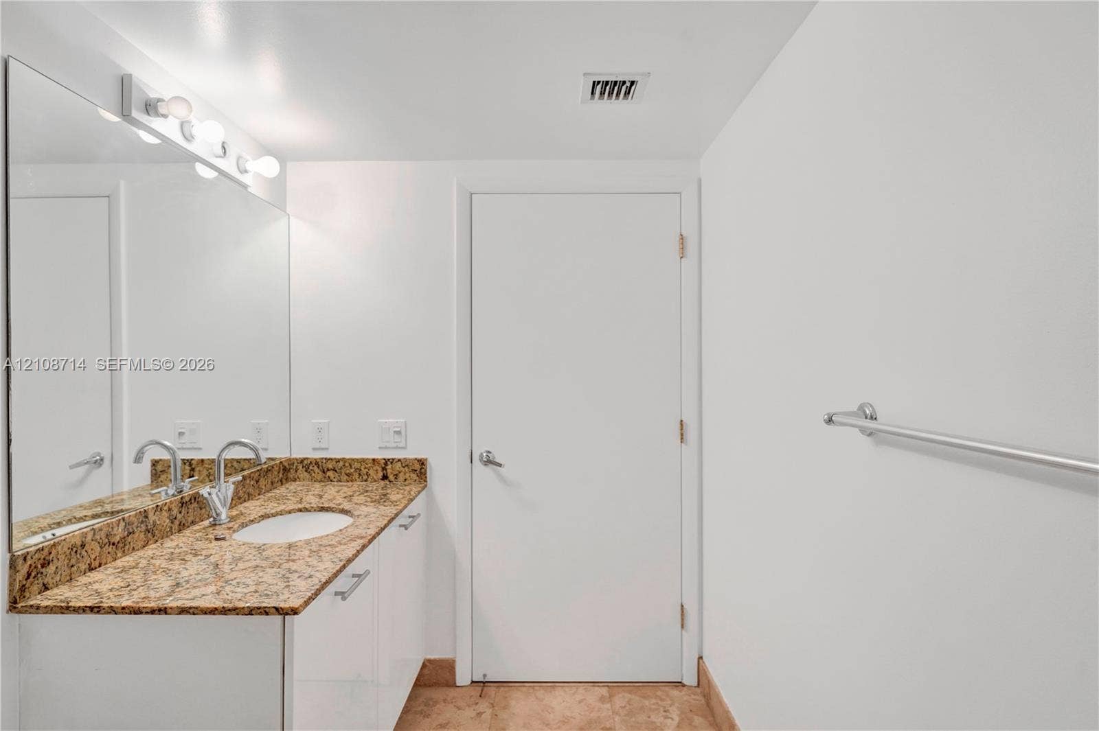 41 SE 5th Street, #317, Miami, Miami, FL 33131 Vanity with stone-finish countertop, integrated oval sink, multi-bulb vanity lighting, full-width wall mirror, and floor-level stone tile