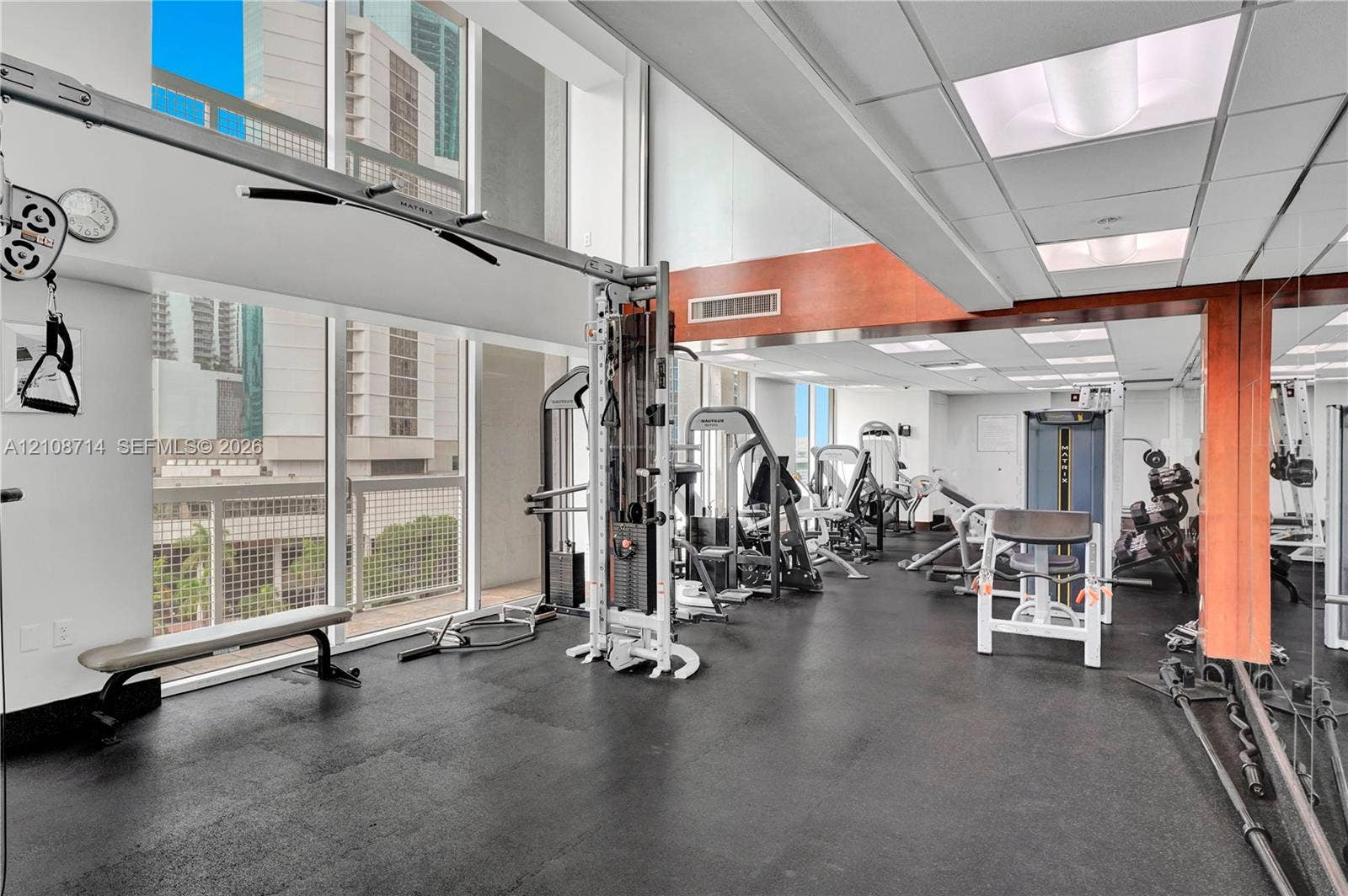 41 SE 5th Street, #317, Miami, Miami, FL 33131 Fitness center featuring floor-to-ceiling windows, rubberized flooring, wood-paneled accents, mirrored walls, and drop-ceiling lighting