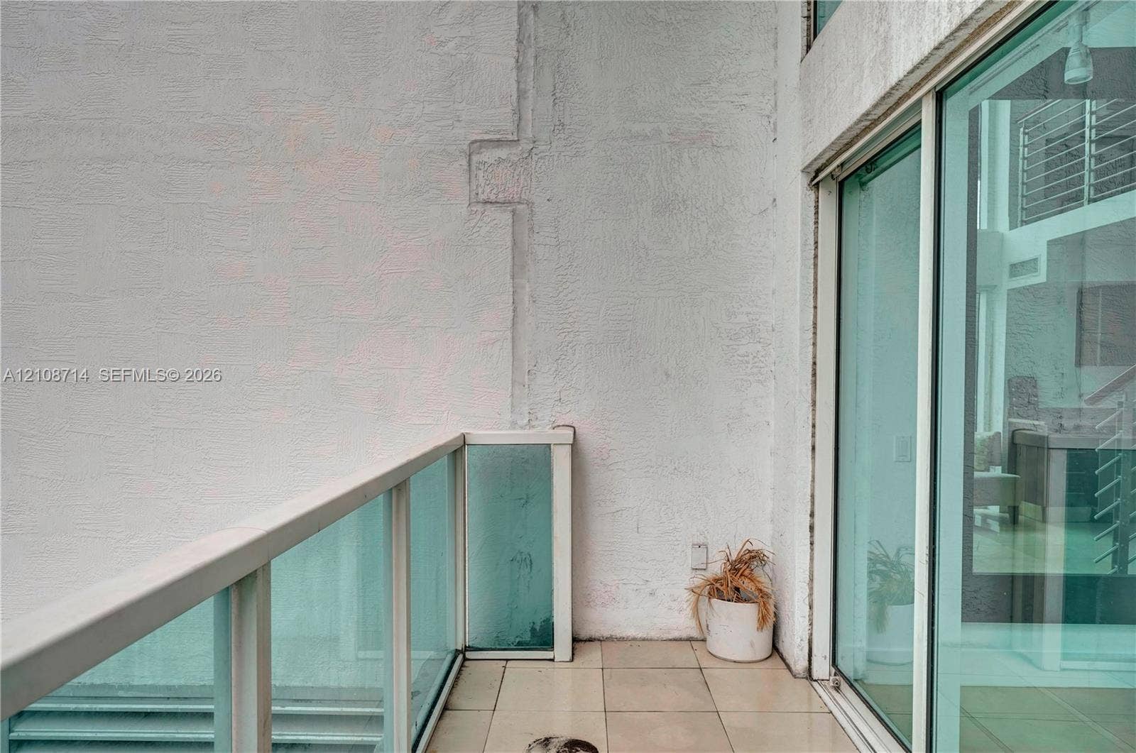 41 SE 5th Street, #317, Miami, Miami, FL 33131 Outdoor terrace featuring large-format neutral floor tiling, a glass panel railing with a white frame, and full-height sliding glass doors