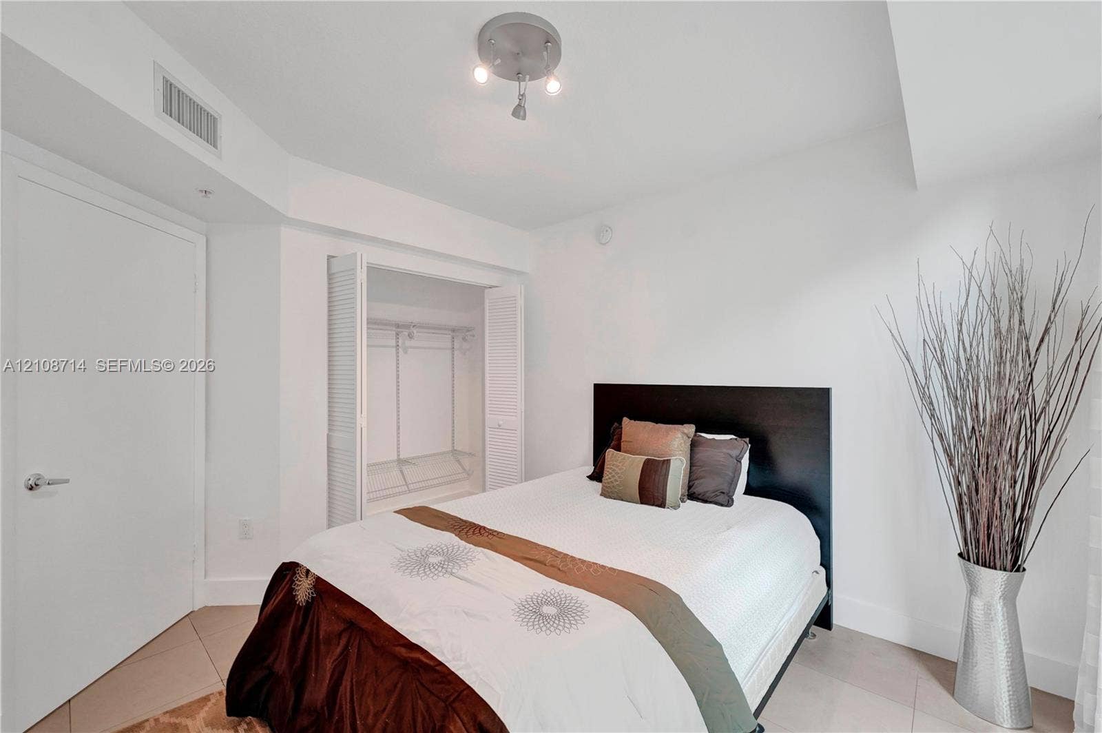 41 SE 5th Street, #317, Miami, Miami, FL 33131 Neutral-toned ceramic tile flooring, a closet with louvered bifold doors, and a three-bulb semi-flush mount ceiling fixture