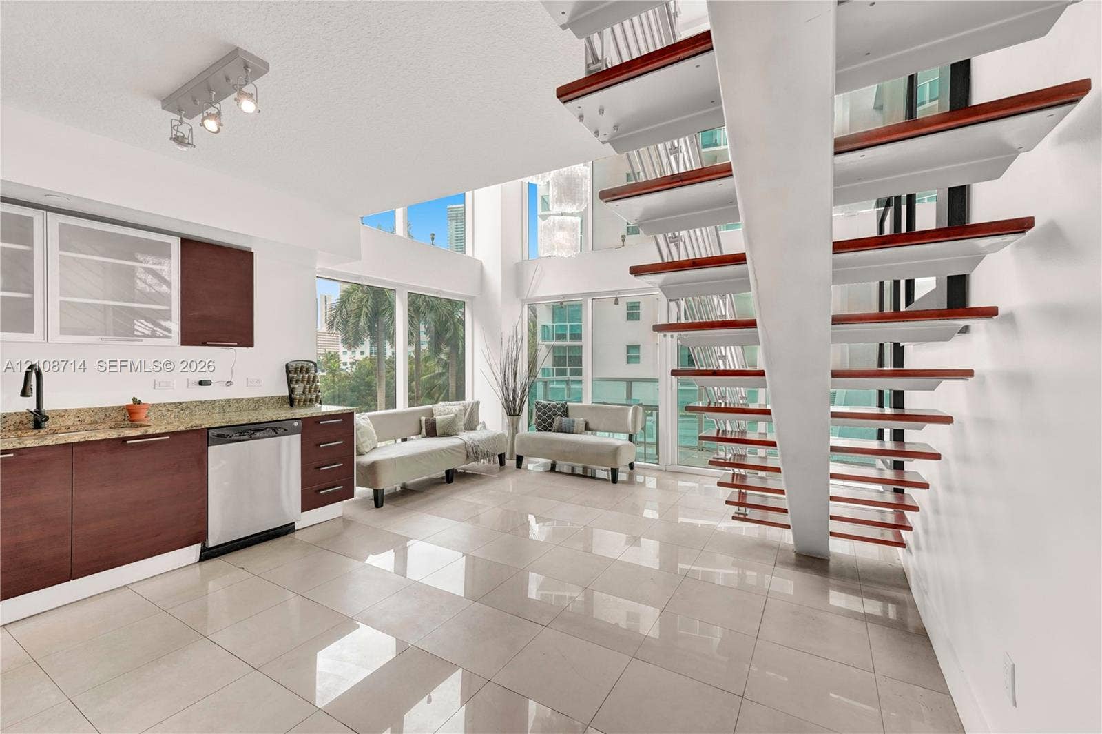 41 SE 5th Street, #317, Miami, Miami, FL 33131 Open-concept interior featuring wood-tread floating staircase, floor-to-ceiling windows, polished tile flooring, and cabinetry with stone-surface countertops