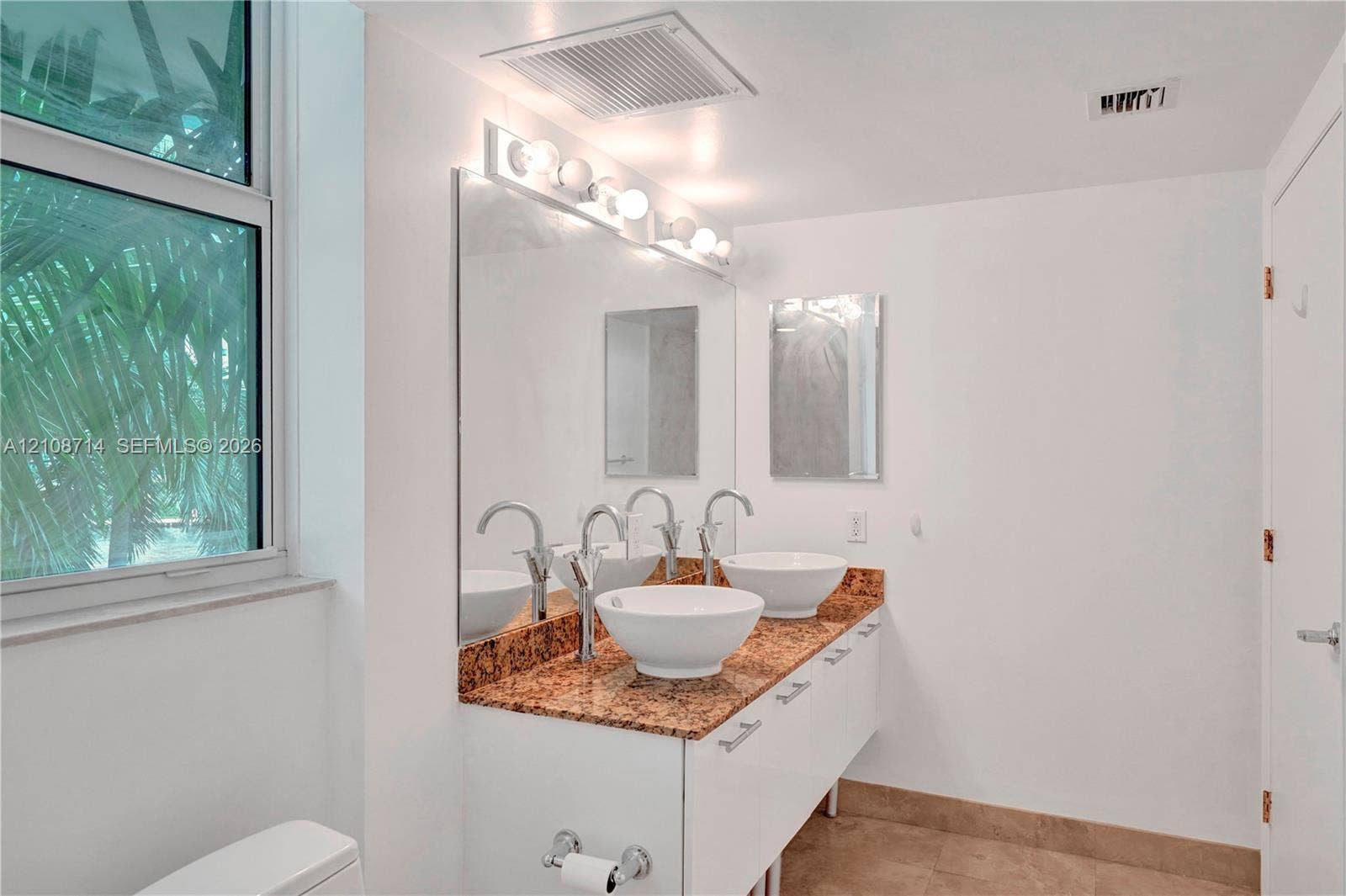 41 SE 5th Street, #317, Miami, Miami, FL 33131 Double vanity featuring white cabinetry, stone-surface countertop, dual vessel sinks, and wall-mounted mirror with integrated lighting