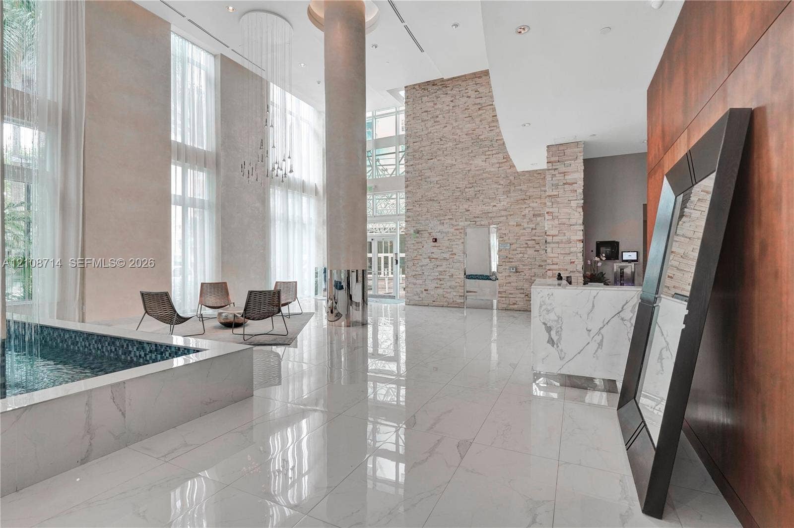 41 SE 5th Street, #317, Miami, Miami, FL 33131 Grand atrium featuring floor-to-ceiling windows, polished stone flooring, a stacked-stone accent wall, a circular structural column, and a built-in water feature with mosaic tiling