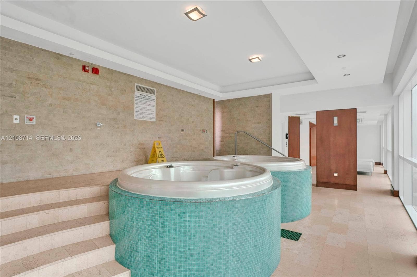 41 SE 5th Street, #317, Miami, Miami, FL 33131 Dual circular jetted tubs with teal mosaic tile surrounds, stone-finish flooring, recessed lighting, and tiered stone stair entry