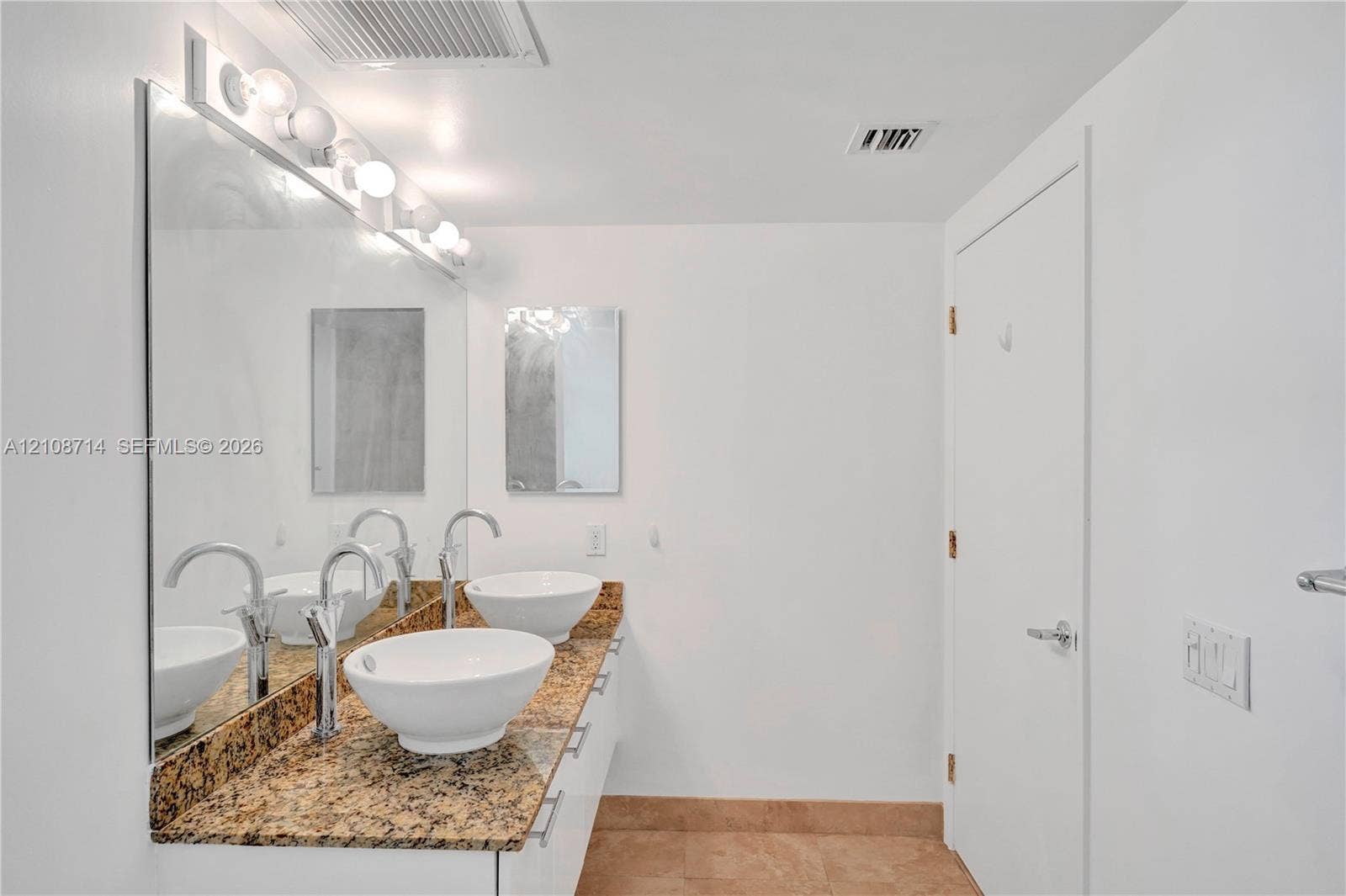 41 SE 5th Street, #317, Miami, Miami, FL 33131 Double vanity featuring vessel sinks, stone-finish countertops, wall-mounted mirror, and multi-bulb lighting fixture