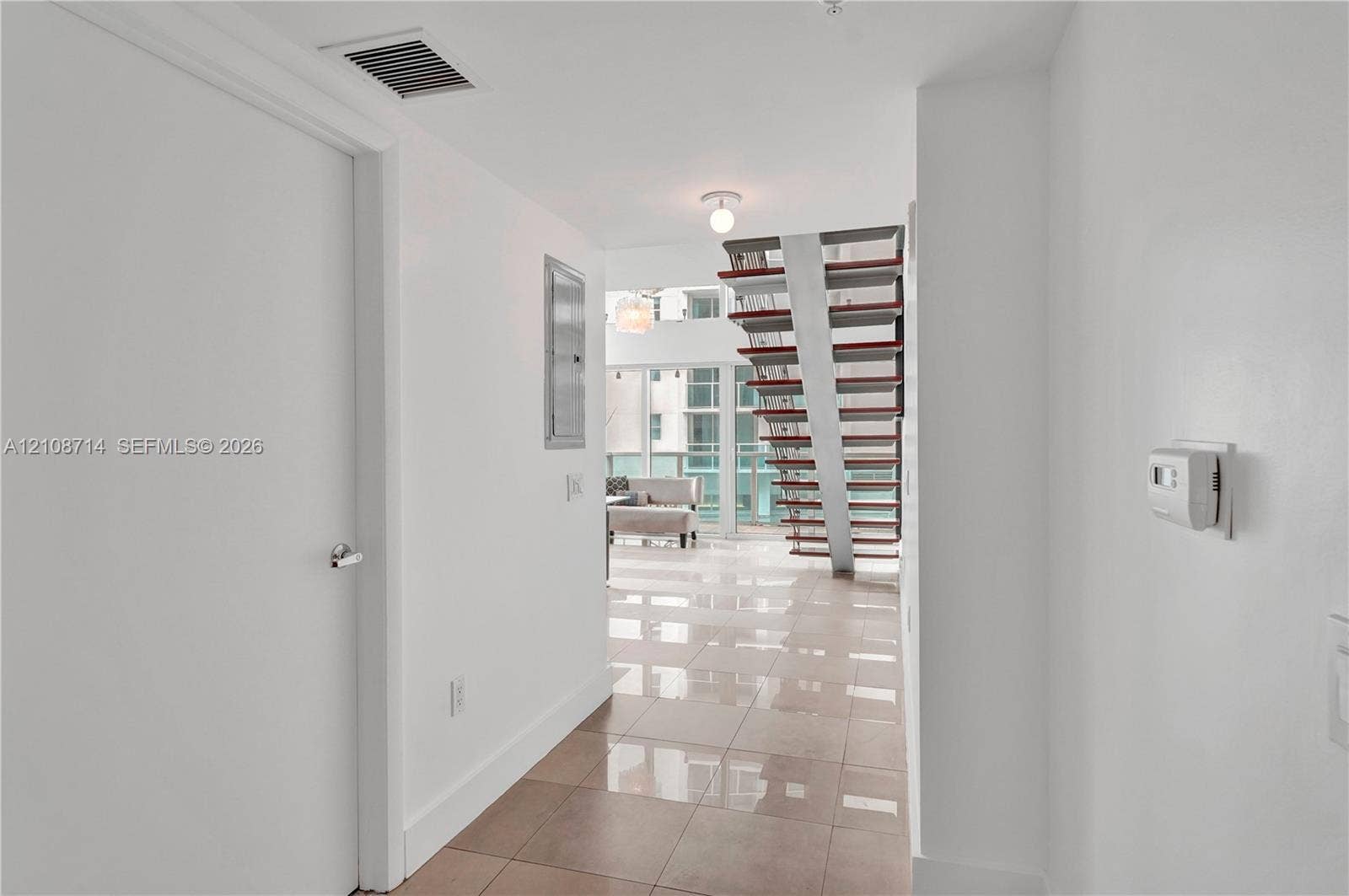 41 SE 5th Street, #317, Miami, Miami, FL 33131 Open-concept interior featuring large-format tile flooring, a custom staircase with metal supports and open risers, and full-height glass windows