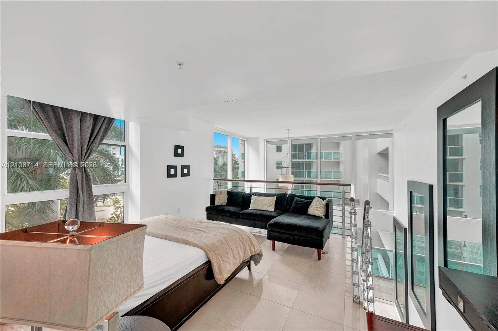 41 SE 5th Street, #317, Miami, Miami, FL 33131 Open-concept loft area featuring large-format tile flooring, expansive floor-to-ceiling windows, and a metal-railed mezzanine overlooking the lower level