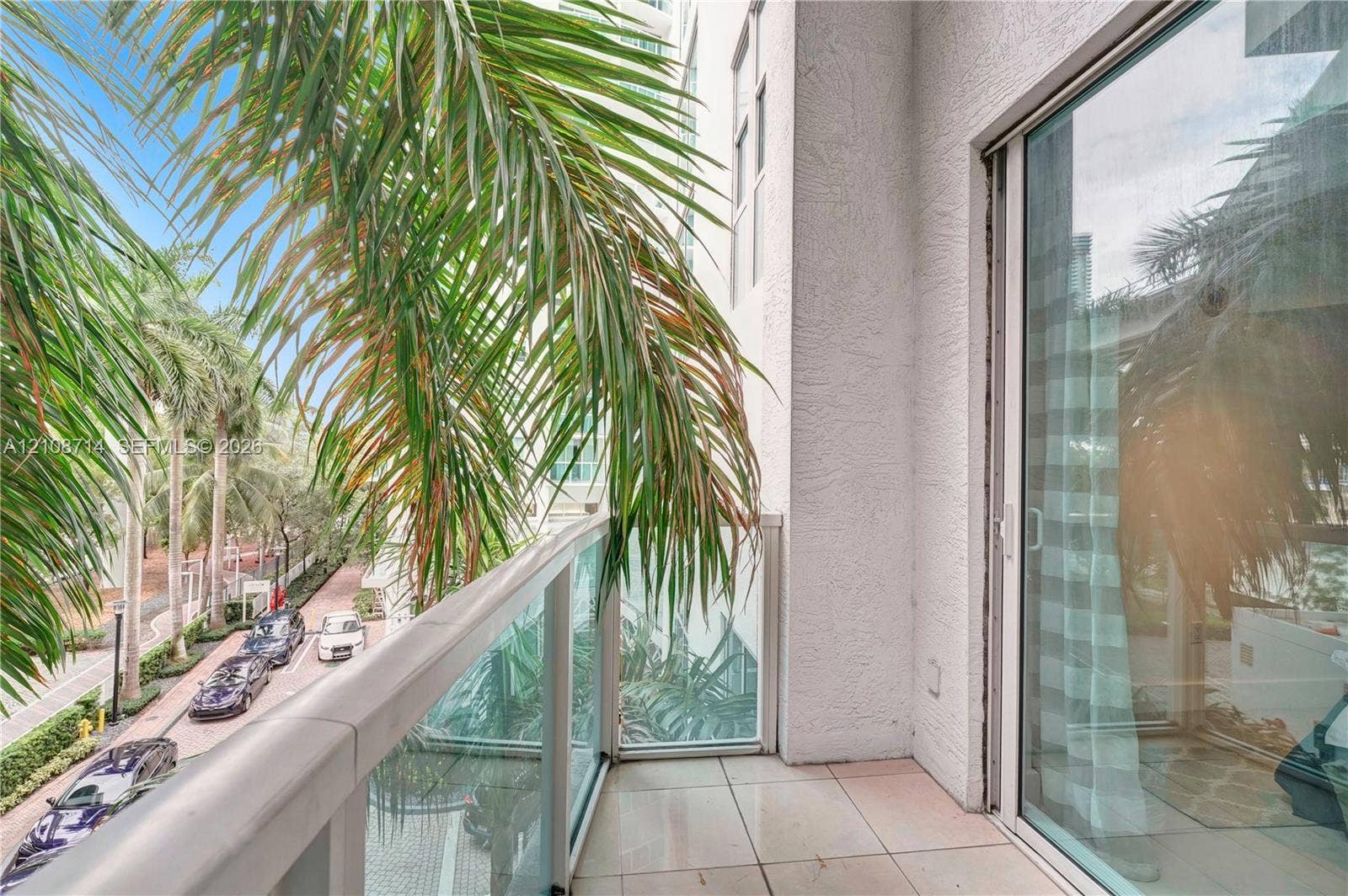 41 SE 5th Street, #317, Miami, Miami, FL 33131 Private balcony featuring tile flooring and a glass railing with a metal frame, accessed by a sliding glass door