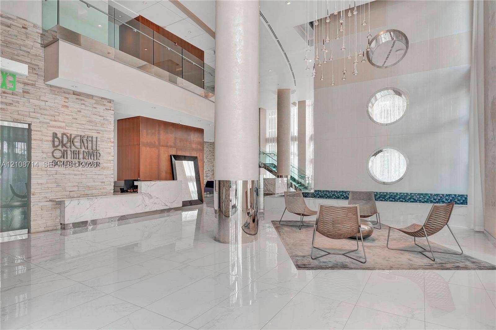 41 SE 5th Street, #317, Miami, Miami, FL 33131 Grand double-height lobby featuring polished stone flooring, stacked-stone accent wall, metal-clad support columns, and geometric tiered chandelier lighting
