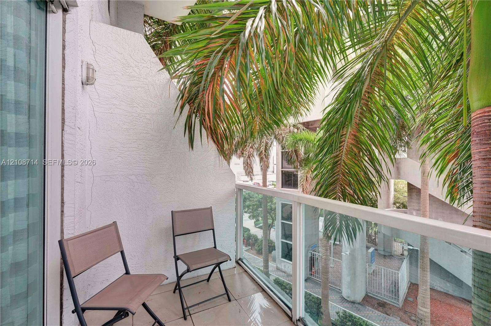 41 SE 5th Street, #317, Miami, Miami, FL 33131 Private balcony featuring textured stucco walls, large-format tile flooring, and a glass-paneled railing