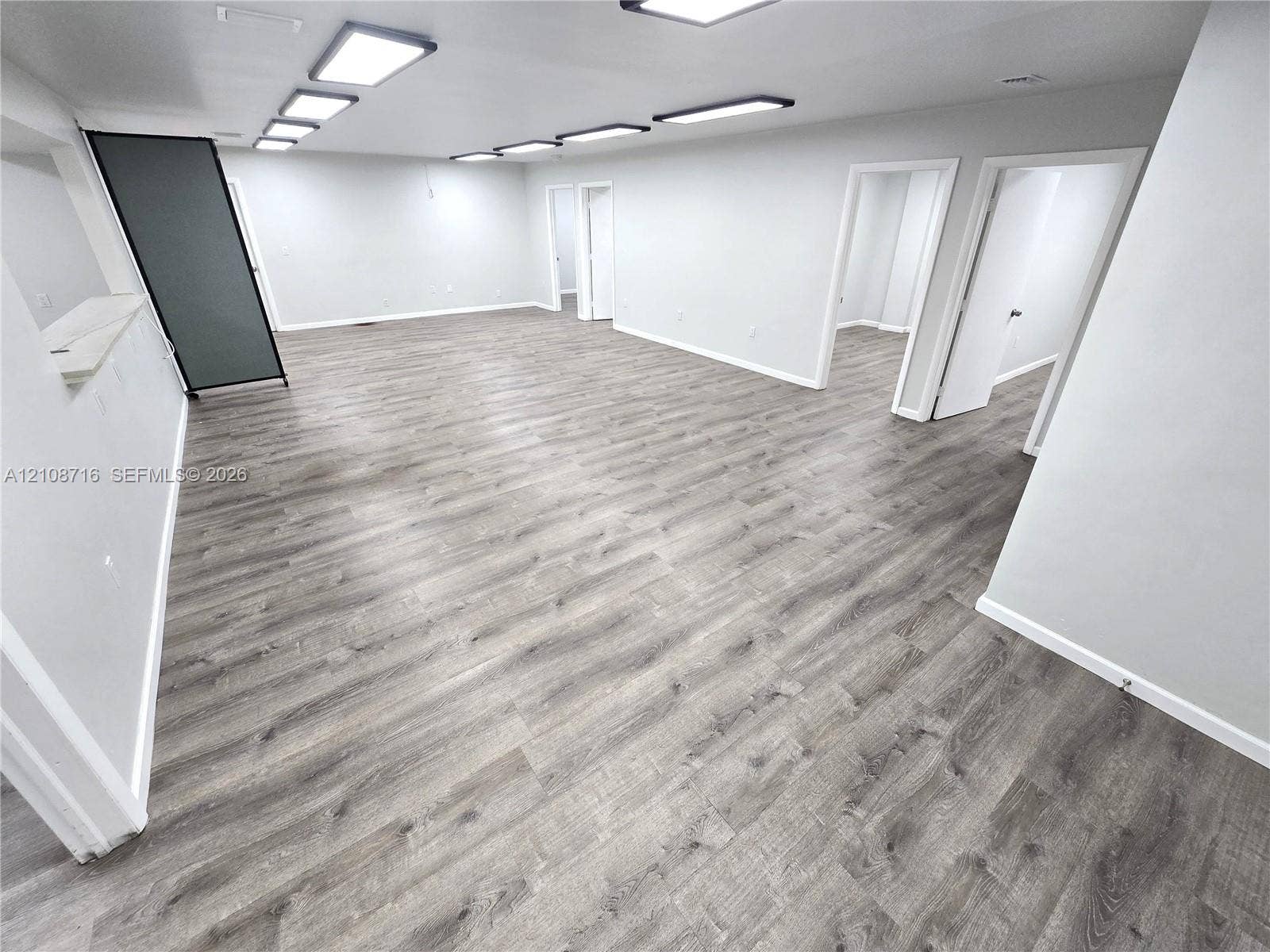 Expansive interior featuring wood-finish flooring, neutral wall paint, and multiple rectangular recessed LED light fixtures