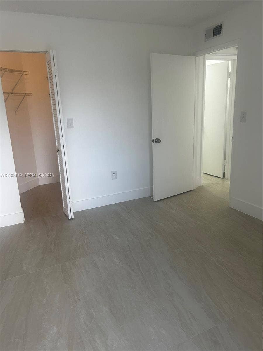 7035 NW 186th Street, #D309, Hialeah, Hialeah, FL 33015 Neutral-toned tile flooring, white interior doors, and a walk-in closet with integrated wire shelving