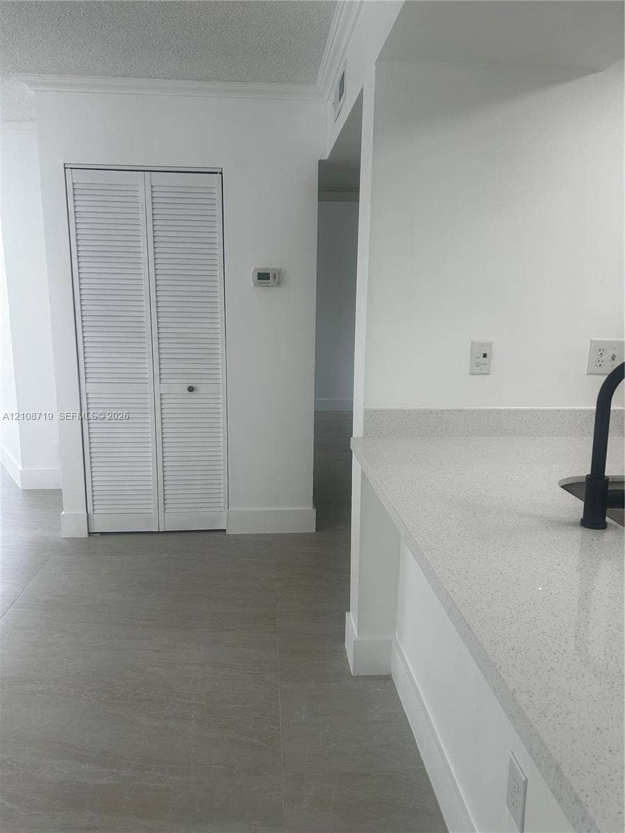 7035 NW 186th Street, #D309, Hialeah, Hialeah, FL 33015 Neutral-toned tile flooring, quartz countertops, matte black faucet, and white louvered-door closet