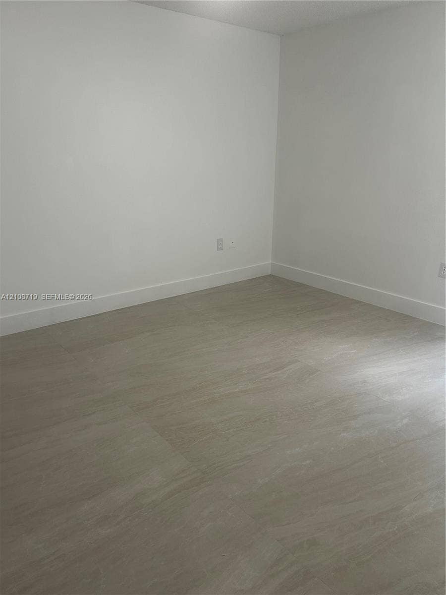7035 NW 186th Street, #D309, Hialeah, Hialeah, FL 33015 Neutral-toned interior space featuring stone-finish flooring and crisp white walls