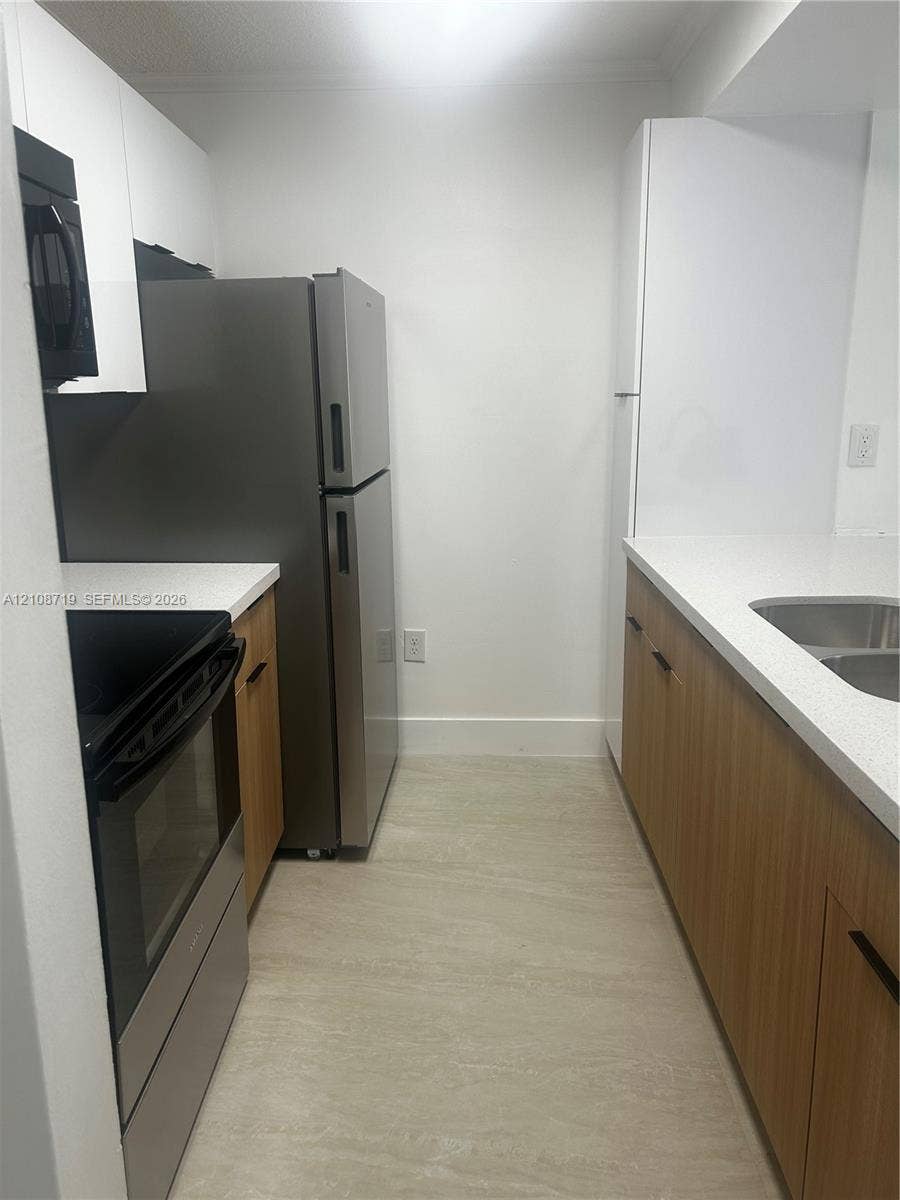 7035 NW 186th Street, #D309, Hialeah, Hialeah, FL 33015 Kitchen featuring stainless steel appliances, light wood-finish cabinetry, white stone-composite countertops, and neutral tile flooring