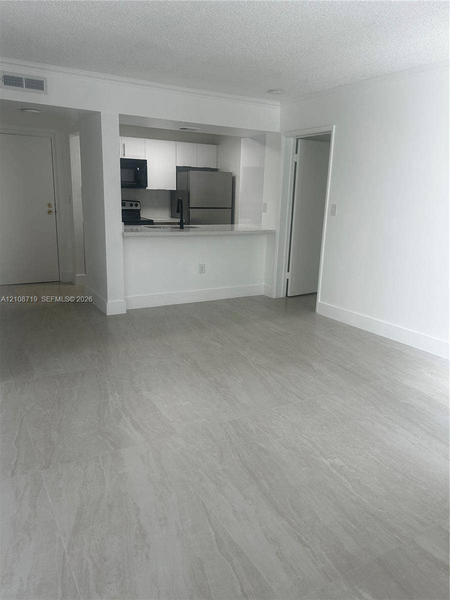 7035 NW 186th Street, #D309, Hialeah, Hialeah, FL 33015 Open-concept living space featuring large-format tile flooring, white cabinetry, a breakfast bar, and stainless steel appliances
