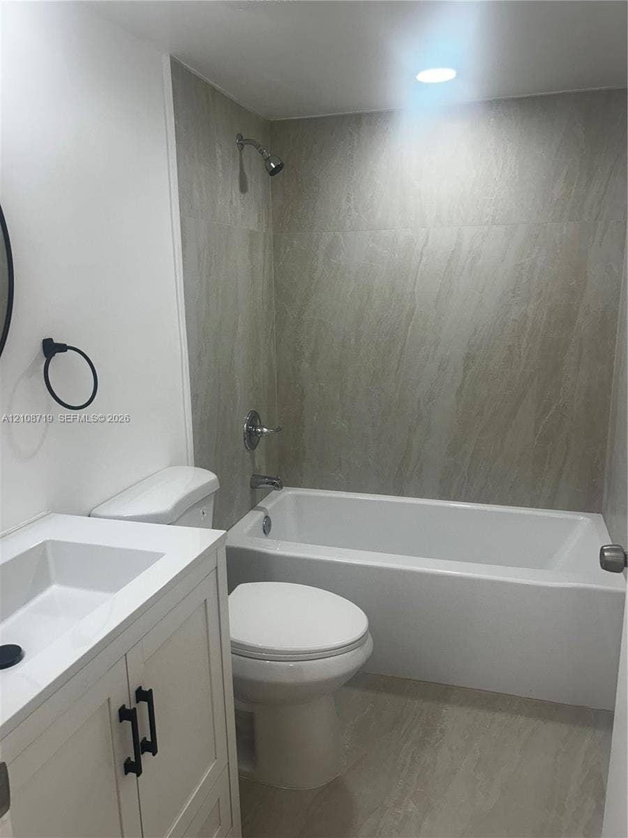 7035 NW 186th Street, #D309, Hialeah, Hialeah, FL 33015 White vanity with a rectangular basin, stone-composite shower surround, recessed ceiling lighting, and matte black hardware fixtures