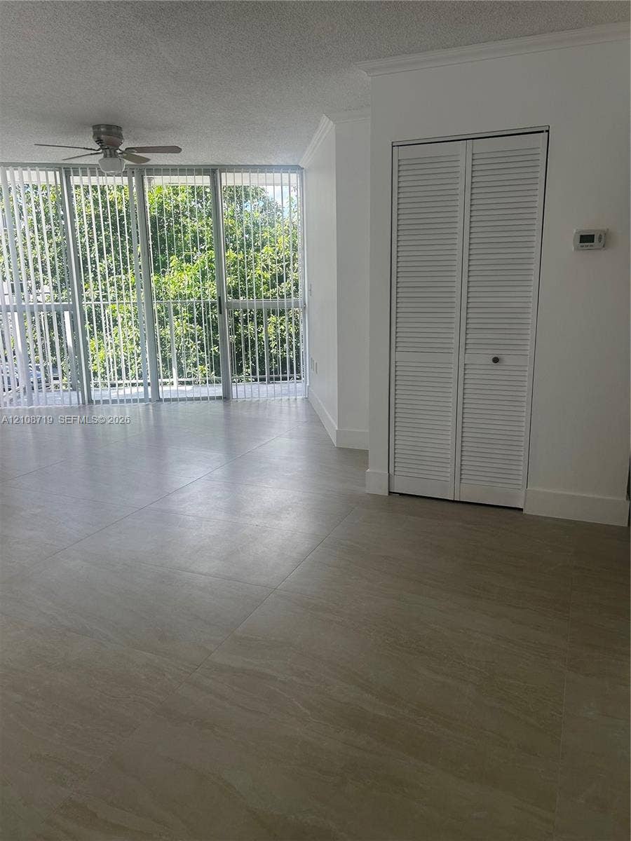 7035 NW 186th Street, #D309, Hialeah, Hialeah, FL 33015 Large-format tile flooring, ceiling fan with integrated light, floor-to-ceiling glass panel windows, and white louvered closet doors