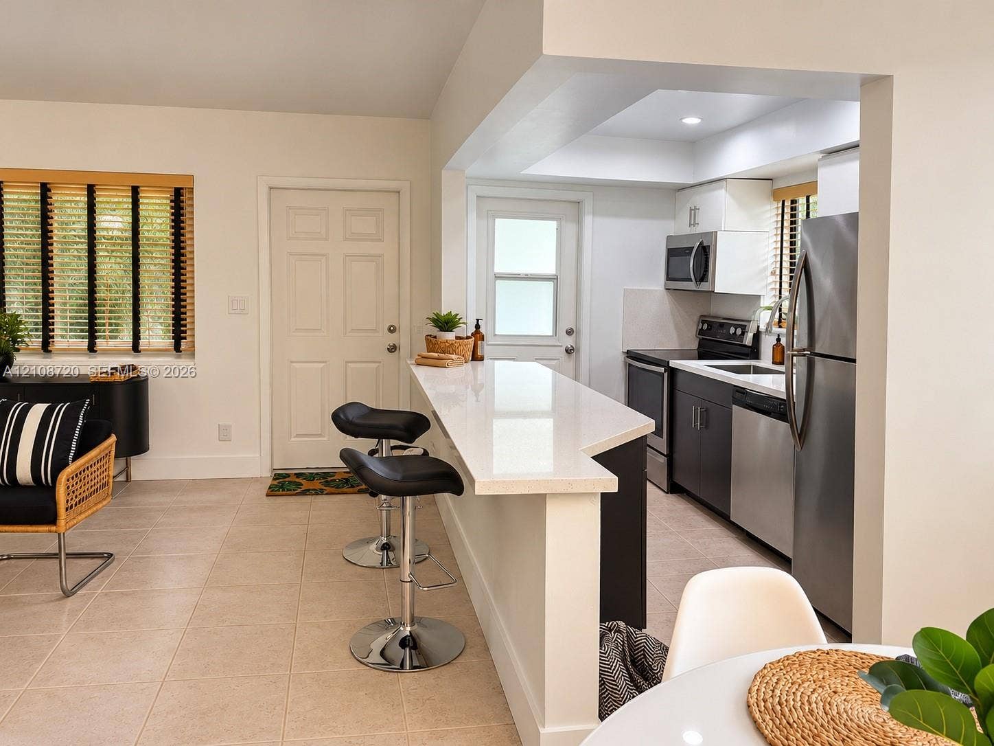 2404 NE 33rd Avenue, #3, Fort Lauderdale, FL 33305 Kitchen featuring a breakfast bar with a solid surface countertop, stainless steel appliances, dark cabinetry, and tile flooring