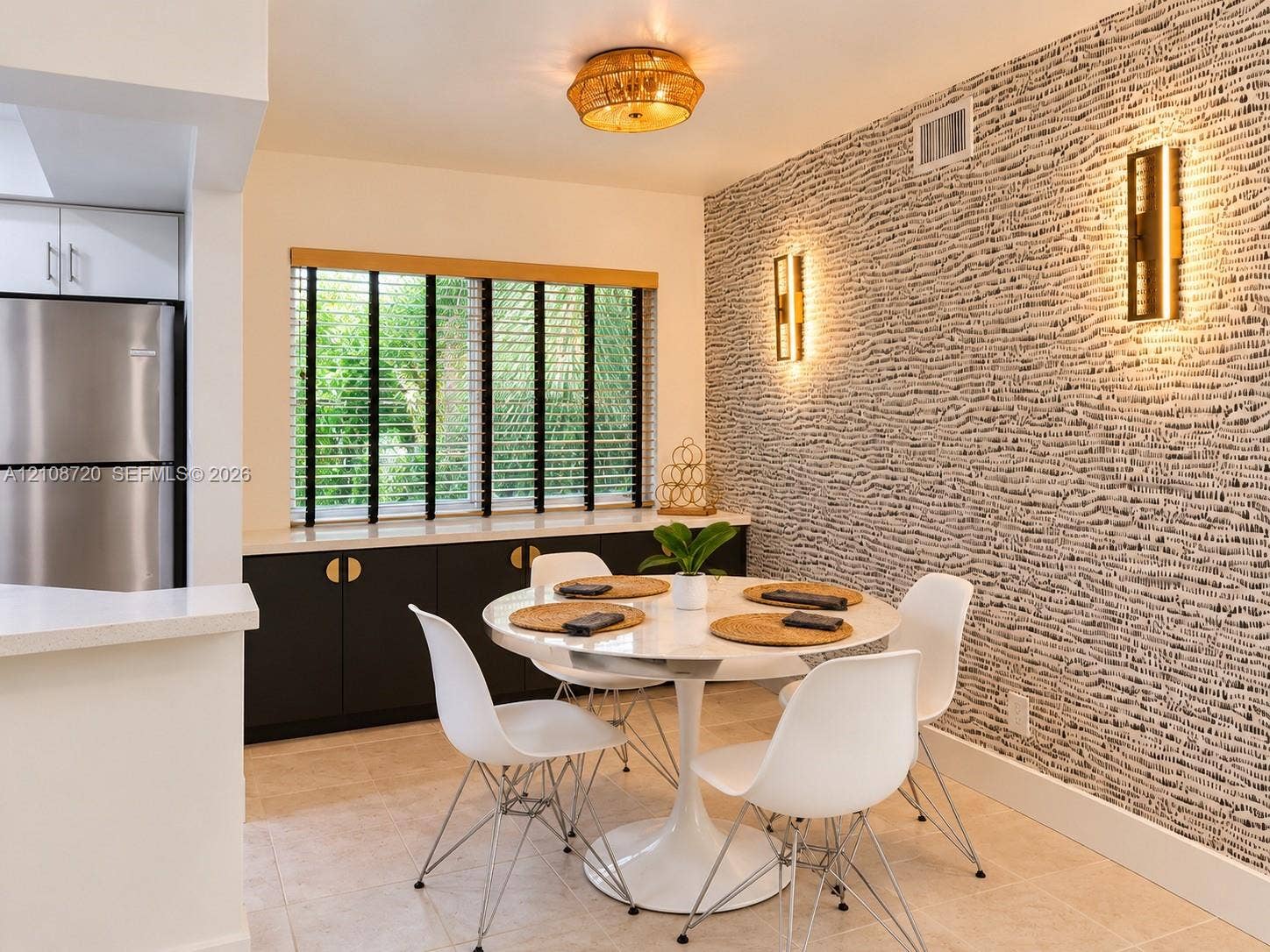 2404 NE 33rd Avenue, #3, Fort Lauderdale, FL 33305 Dining area featuring a statement textured accent wall, built-in cabinetry with metallic hardware, dual wall-mounted light fixtures, and a flush-mount overhead light