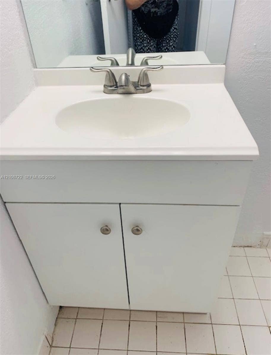 505 NW 177th Street, #110, Miami Gardens, Miami Gardens, FL 33169 White vanity cabinet with integrated basin, polished metal dual-handle faucet, and rectangular wall-mounted mirror