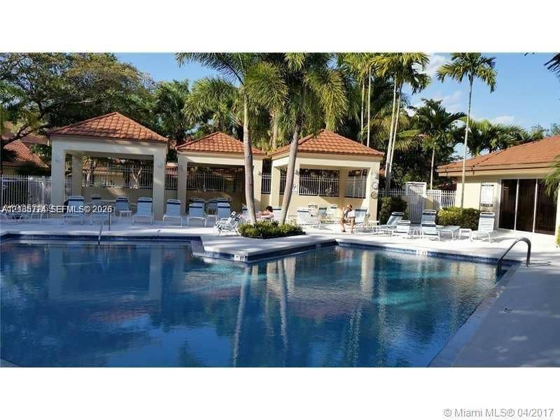 972 NW 92nd Terrace, Plantation, Plantation, FL 33324 In-ground swimming pool featuring a tiled perimeter and concrete decking, surrounded by multiple covered pavilion structures with clay-tile roofs and mature palm trees