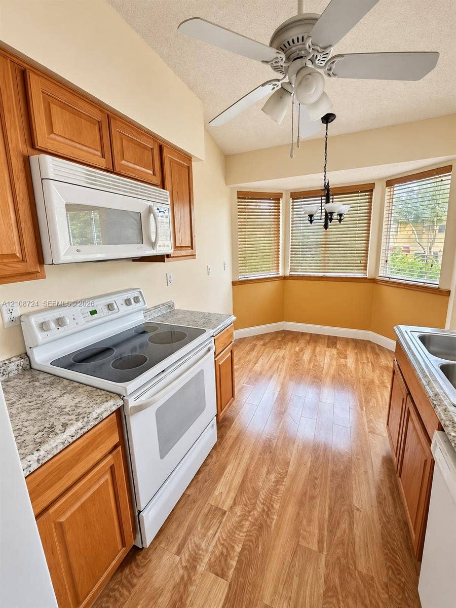 972 NW 92nd Terrace, Plantation, Plantation, FL 33324 Kitchen featuring wood-finish cabinetry, stone-patterned countertops, a white electric range, wood-finish flooring, and a multi-windowed alcove