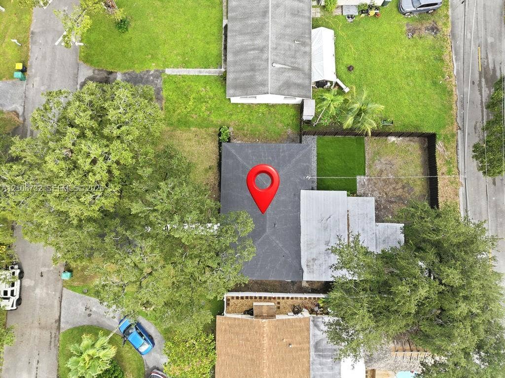 Aerial perspective of property lot featuring mature trees, fenced perimeter, and maintained grass areas