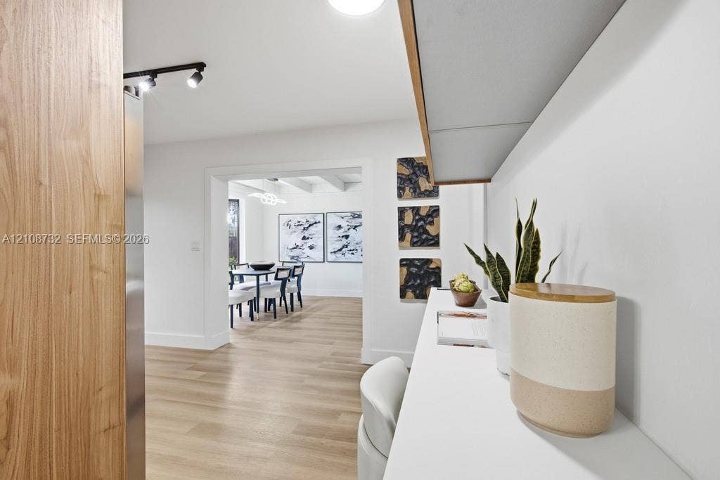 Built-in white desk with overhead shelving, wood-finish flooring, and black track lighting