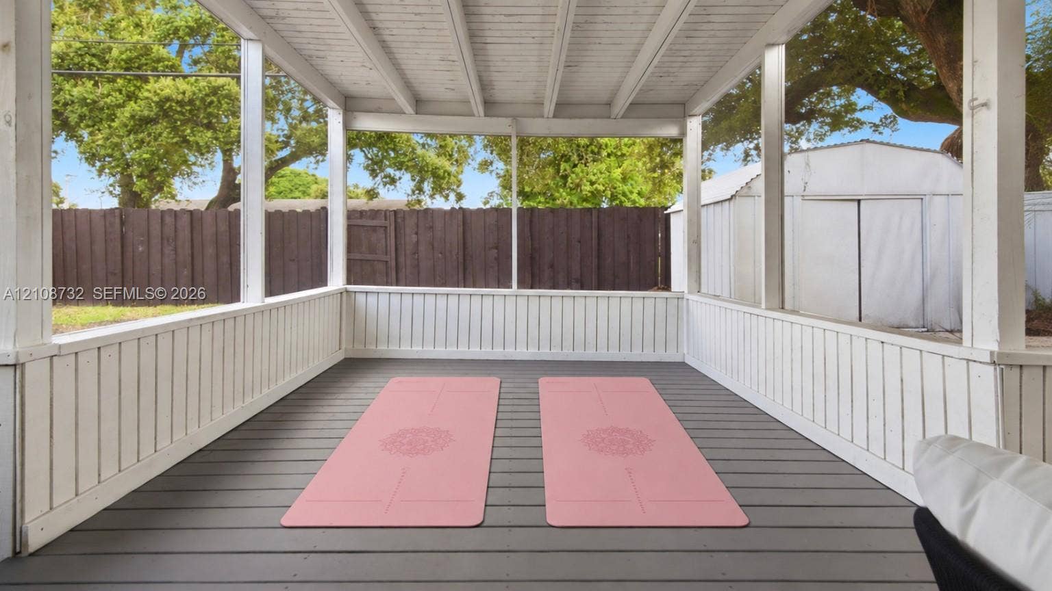 Screened porch featuring painted wood railings, a composite floor, and an exposed beamed ceiling