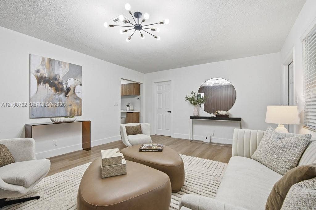 Interior space featuring wood-finish flooring, a multi-arm sputnik-style ceiling light fixture, and a white interior door with black hardware