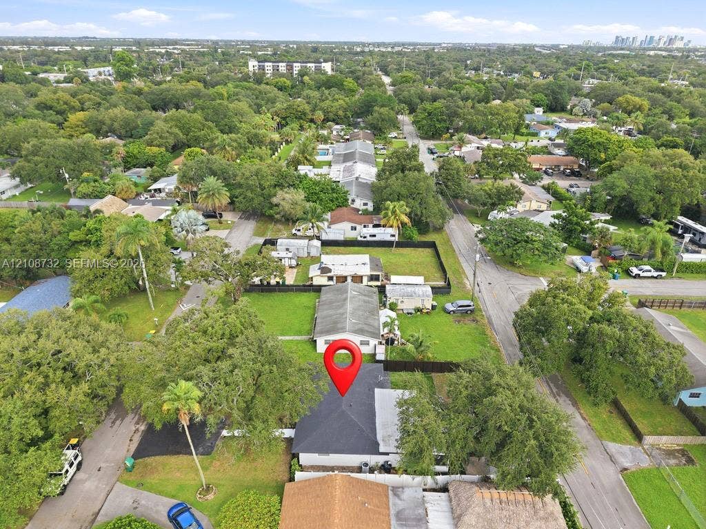 Aerial perspective featuring a residential lot with mature trees and perimeter fencing