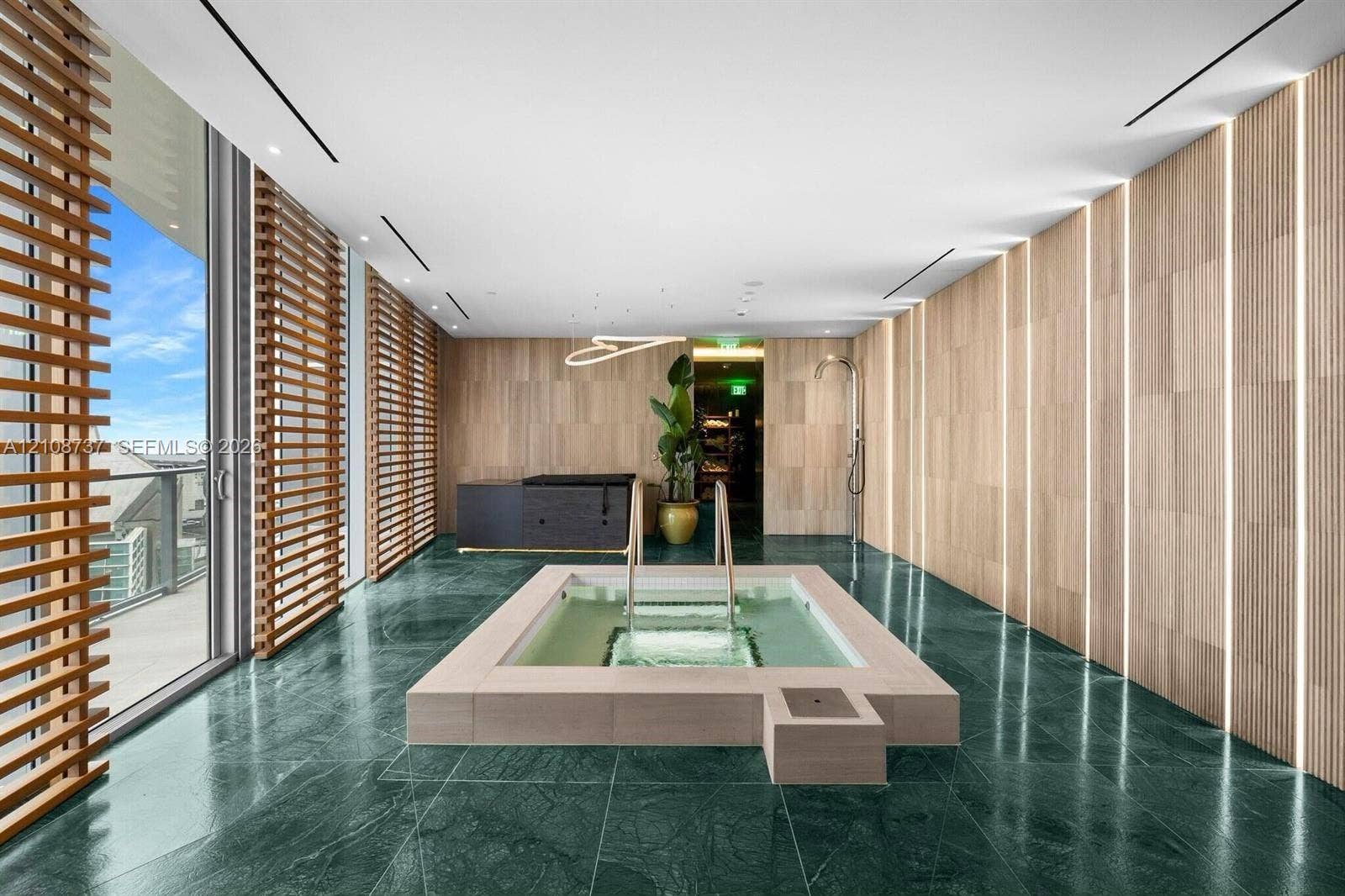 1400 Biscayne Boulevard, #3503, Miami, Miami, FL 33132 Sunken spa with a stone surround, floor-to-ceiling wood-paneled walls with integrated vertical lighting, green stone flooring, and expansive wood-slat privacy screens