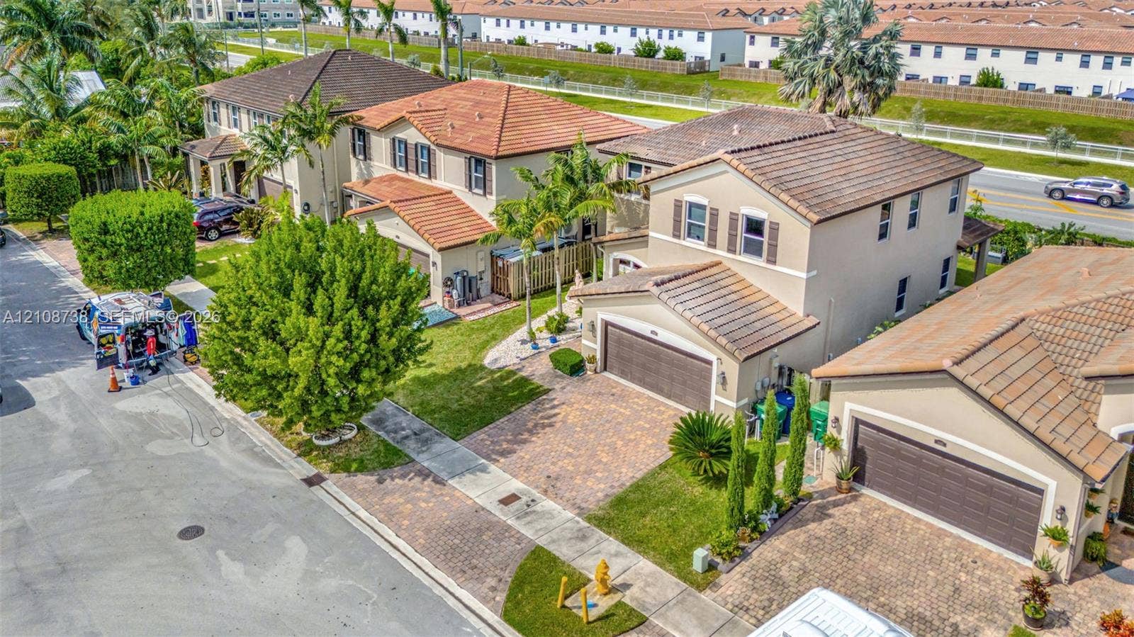 Two-story residence featuring a tile roof, stucco exterior, paver driveway, and an attached two-car garage
